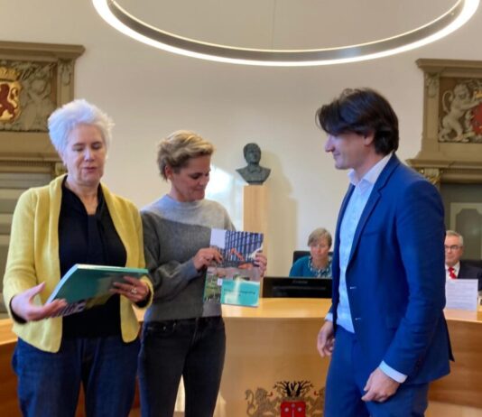Programmabegroting 2025 Met realisme door met Actie Wethouder Roduner overhandigde de Programmabegroting aan raadleden Van Zetten (l. Hart voor Haarlem) en Klazinga (r. VVD).