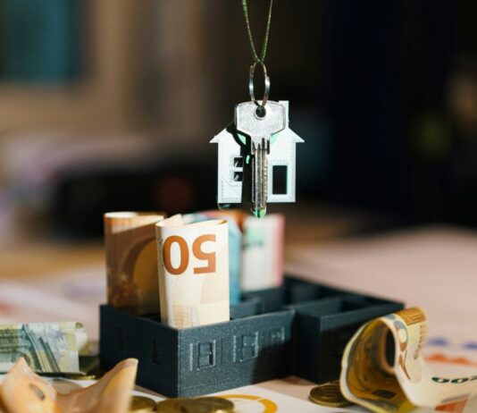 Duurdere huurwoningen massaal in de verkoop: vrije sector krimpt verder door A house hanging from a string on top of a pile of money